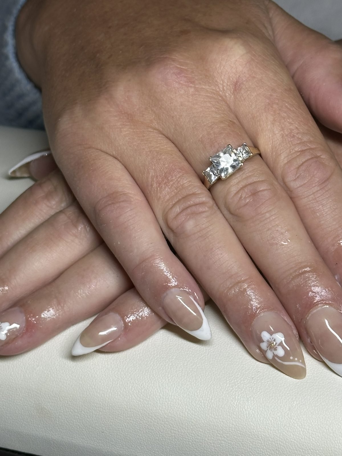 Nude almond acrylic set with white French tips and a hand-sculpted floral accent nail